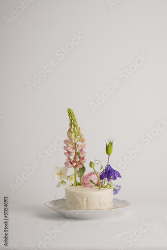 White cake for one person decorated with flowers with lupine