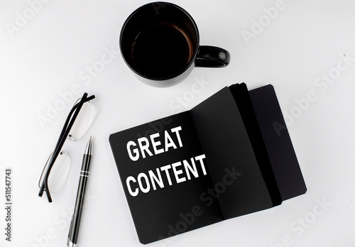 GREAT CONTENT written text in small black notebook with coffee , pen and glasess on white background. Black-white style