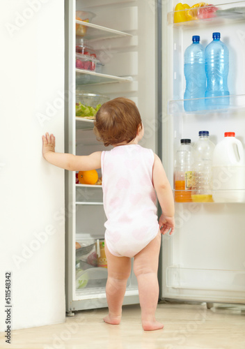 Snack time. Shot of a toddler eating food from the fridge.