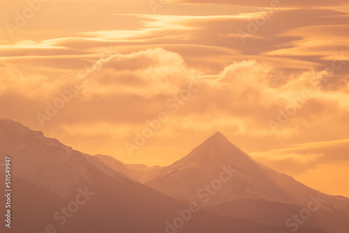 silueta de montañas con nubes anaranjadas del atardecer brillante, hora dorada en montañas 