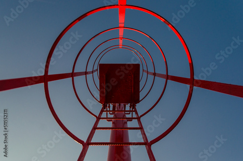 La scala rossa di un piccolo faro in un porto 