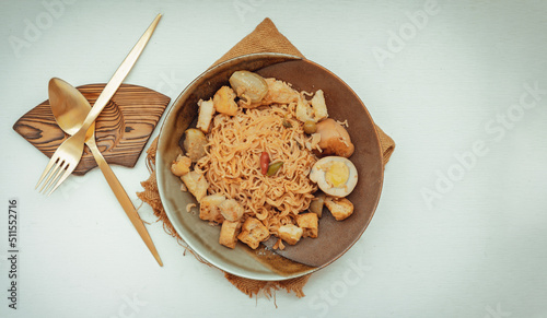 Stir fried instant noodles with green curry with chicken (Kaeng khiao wan) and Boiled egg in sweet brown sauce in ceramic bowl served with cutlery set. Easy noodle thai food, Top view, Copy space,  photo