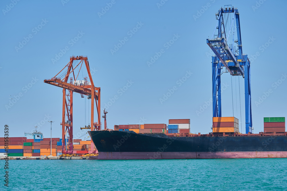 Port crane loading and unloading containers onto a ship. Maritime trade concept