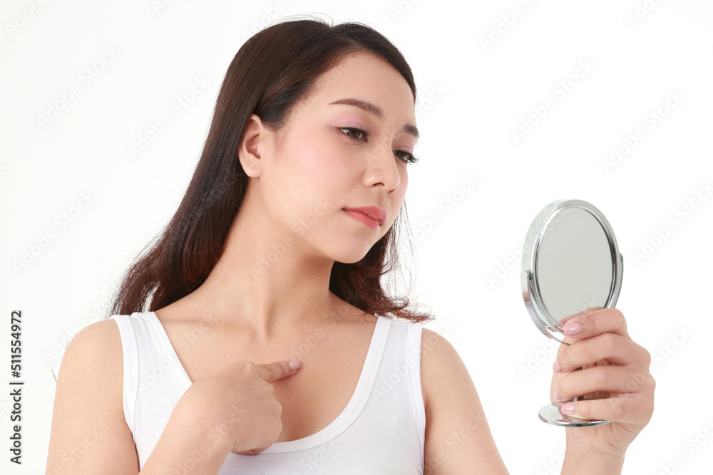 Beautiful Asian woman holding a mirror to look at pimples on her chest. She was very stressed. Beauty concept, beautification, beauty skin care. white background Beautiful Asian woman holding a mirror to look at pimples on her chest. She was very stressed. Beauty concept, beautification, beauty skin care. white background