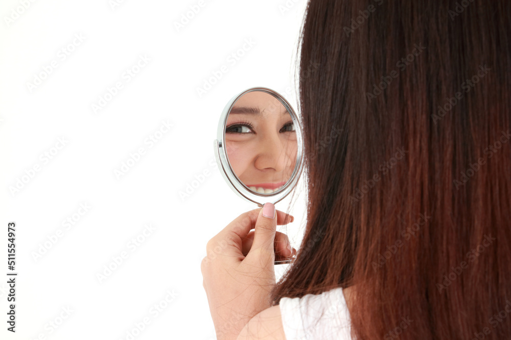 Beautiful Asian woman holding a mirror looking at her face. She smiled happily. Beauty concept, beautification, beauty skin care. white background. Copy space Beautiful Asian woman holding a mirror looking at her face. She smiled happily. Beauty concept, beautification, beauty skin care. white background. Copy space