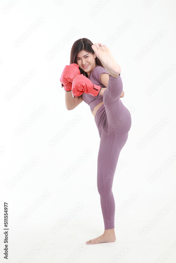 Beautiful Asian woman in good shape wearing purple workout clothes with red boxing gloves doing a kick. on a white background. Concept of exercise, weight loss, health care. Beautiful Asian woman in good shape wearing purple workout clothes with red boxing gloves doing a kick. on a white background. Concept of exercise, weight loss, health care.