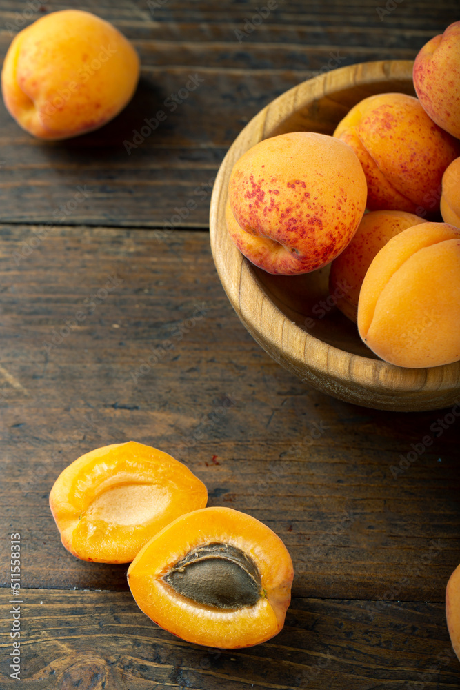Fresh apricots in a wooden plate. Fruits are scattered on a wooden table.