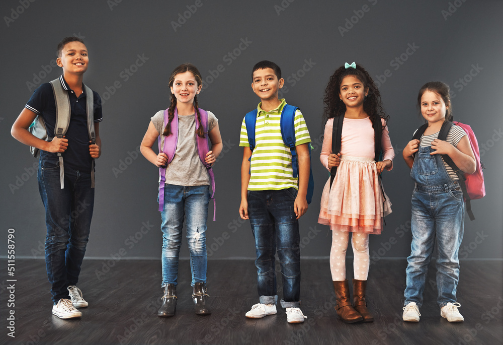 Obraz premium Little people, big day. Studio portrait of a diverse group of kids carrying their school backpacks against a gray background.