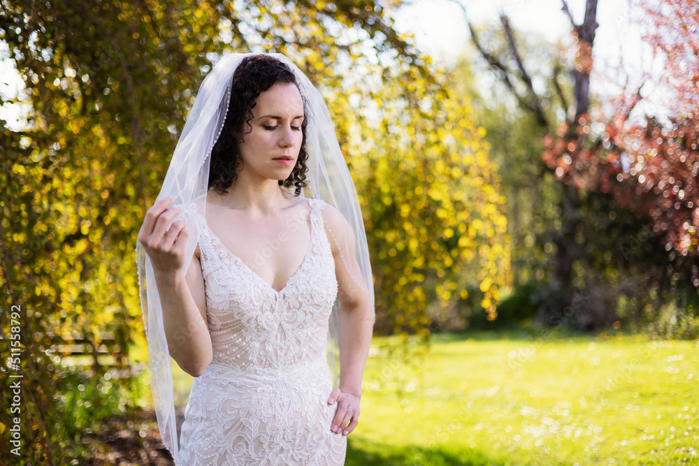 White Caucasian Adult Woman in a Wedding Dress standing outside in nature. Queen Elizabeth Park, Vancouver, British Columbia, Canada. Bride