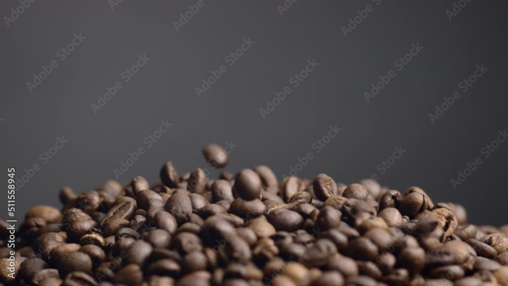 Coffee beans falling down on heap close up. Roasted grains pouring background. Coffee beans falling down on heap close up. Roasted grains pouring background.