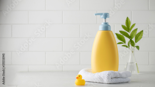 Yellow bottle of children cosmetic product and toy rubber duck in bathroom. Copy space