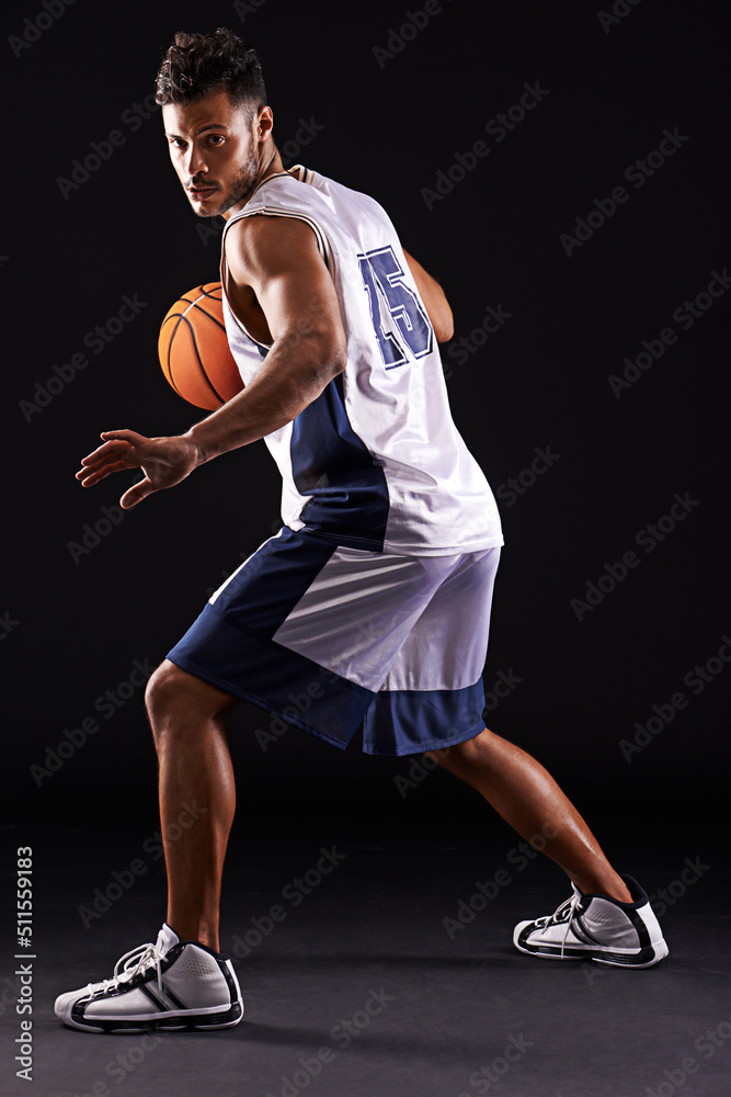 Defend defend defend. Studio shot of a basketball player against a black background. Defend defend defend. Studio shot of a basketball player against a black background.