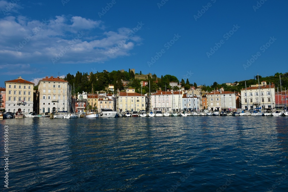Piran, Slovenia - May 10 2022: View of the coastal town of Piran in Slovenian Istria and a hill above with the old medieval wall of Piran