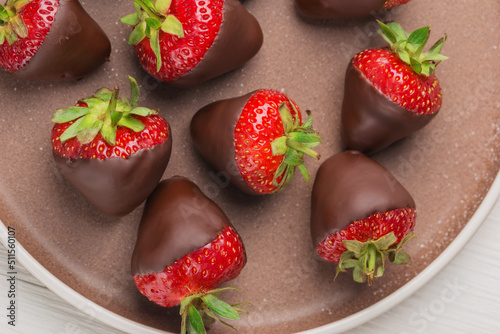 Top view on ceramic plate with dark chocolate covered strawberries. Gourmet food.