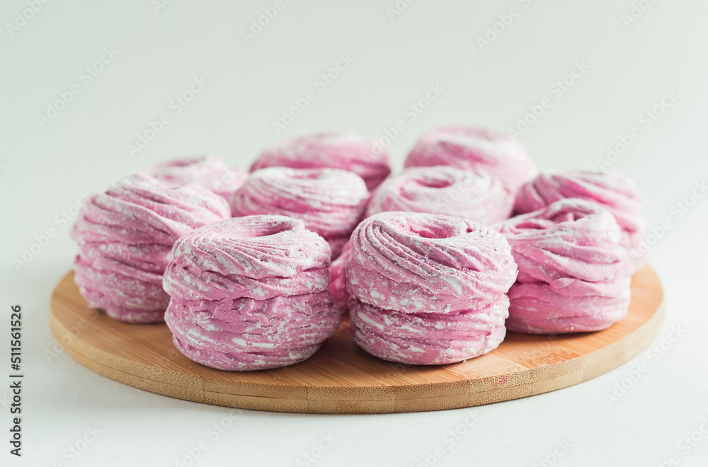 Obraz premium Pink marshmallow in the wooden plate on the white background