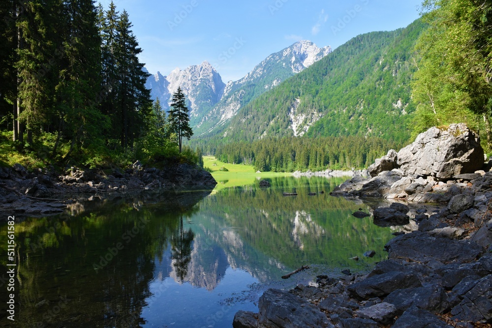View of a bay at Laghi di Fusine Superiore in Comune di Tarvisio in Italy and forest covered mountains