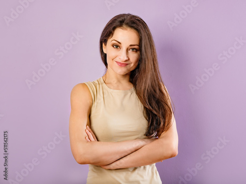 Beautiful happy smiling woman with folded arms in casual beige clothing on purple background with empty copy space. Closeup