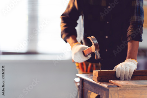 Slika na platnu The carpenter is hammering nails into the wood. in the workshop