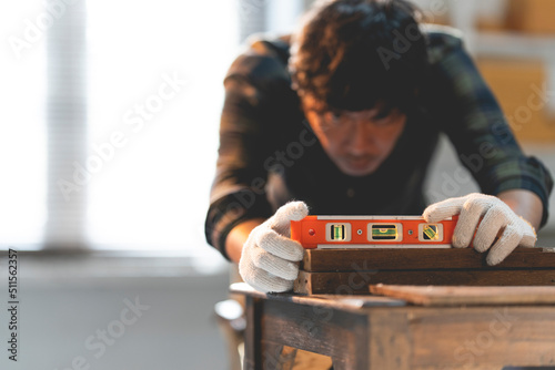 A male craftsman is using a wooden spirit level in his workshop.