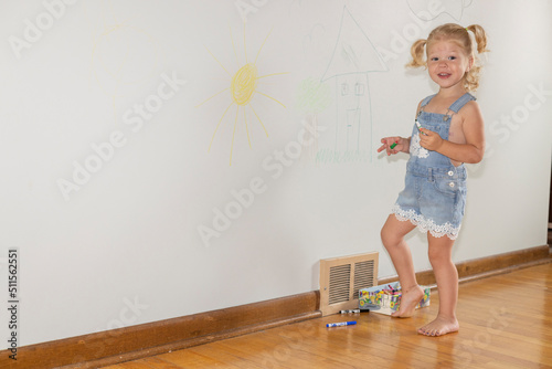 Foto Naughty child coloring on the walls inside her home and not doing what she is su