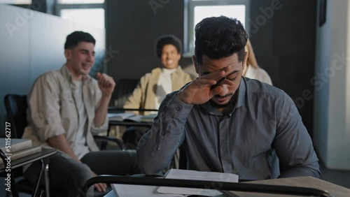 Frustrated oppressed indian student sitting in class lonely young guy suffers from abuse bullying by classmates ridicule mockery bad attitude upset worried man feeling offended disappointed depression