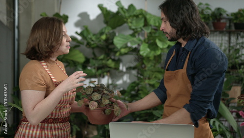 Two employees discussing online orders at small business flower shop. Male and female staff comparing inventory