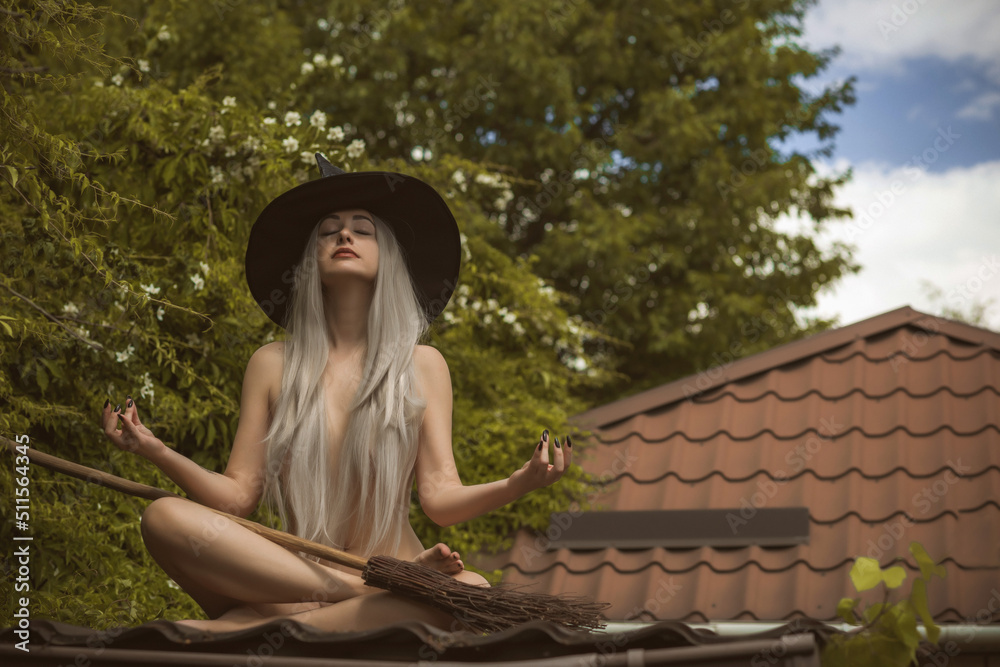 Obraz premium Young beautiful and mysterious Witch woman Flying on the Broom. Levitation, a witch in a hat flies on a broom, free space. Halloween holiday, magic