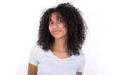 Stunned Young beautiful girl with afro hairstyle wearing gray t-shirt over white background stares reacts on shocking news. Astonished girl holds breath