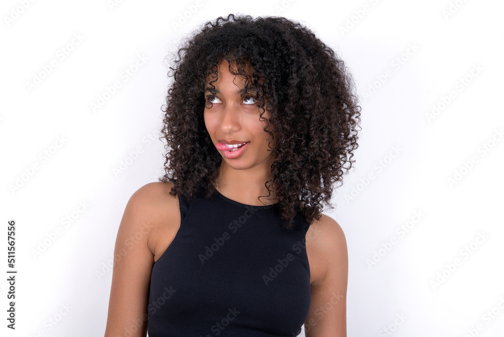 Young beautiful girl with afro hairstyle wearing black tank top over white background showing grimace face crossing eyes and showing tongue. Being funny and crazy Young beautiful girl with afro hairstyle wearing black tank top over white background showing grimace face crossing eyes and showing tongue. Being funny and crazy