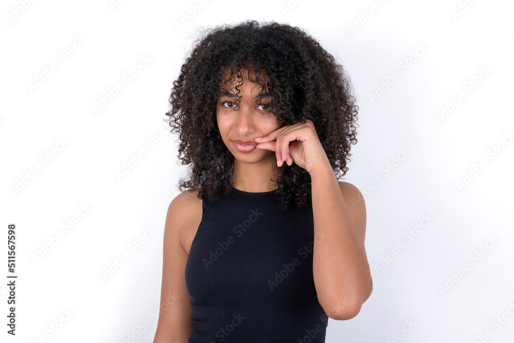 Young beautiful girl with afro hairstyle wearing black tank top over white background mouth and lips shut as zip with fingers. Secret and silent, taboo talking.