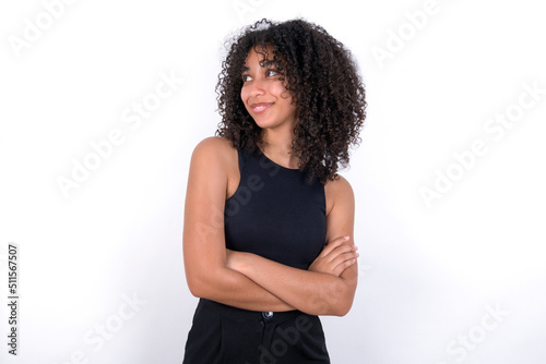 Dreamy rest relaxed Young beautiful girl with afro hairstyle wearing black tank top over white background crossing arms, looks good copyspace