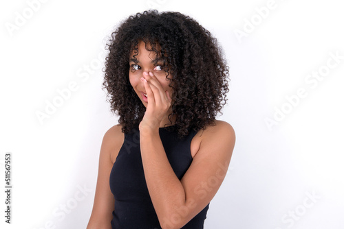 Young beautiful girl with afro hairstyle wearing black tank top over white background hear incredible private news impressed scream share © Roquillo