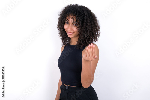 Young beautiful girl with afro hairstyle wearing black tank top over white background inviting to come with hand. Happy that you came