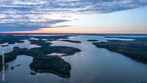 Aerial view of the lake and green islands on the water during sunset. 