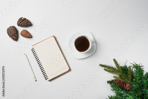 Christmas home office desk with notebook, cup of coffee and christmas decorations on white backgraund. Christmas card background notebook template. Top view with space for text.