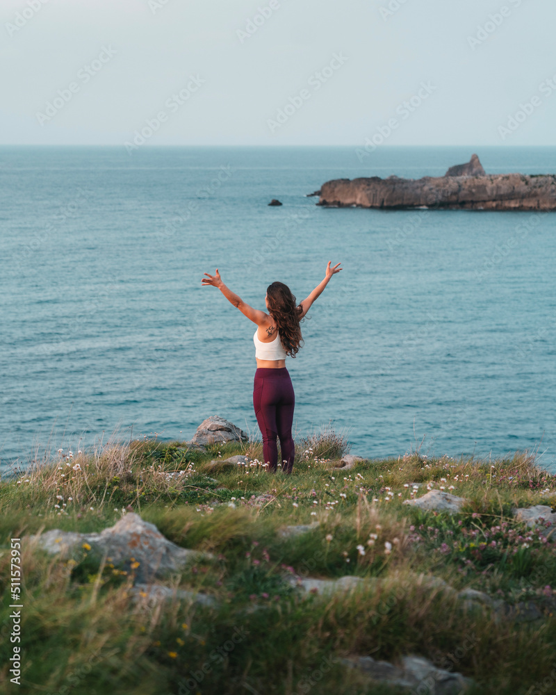 Anonymous woman doing yoga on cliff in front of wavy sea Anonymous woman doing yoga on cliff in front of wavy sea