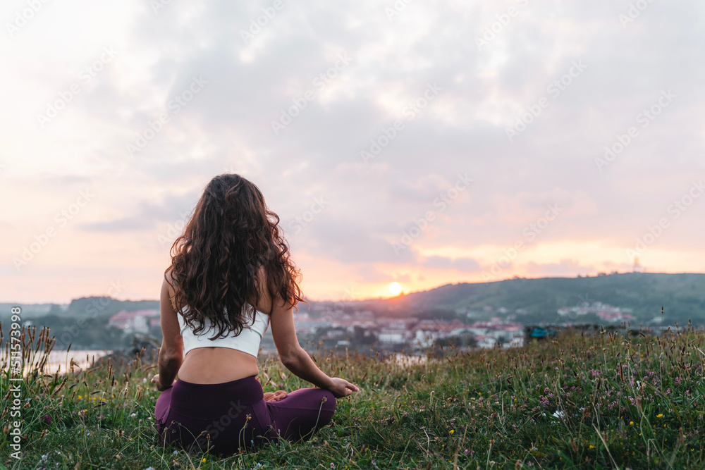 Young woman sitting in Lotus pose and meditating in nature Young woman sitting in Lotus pose and meditating in nature