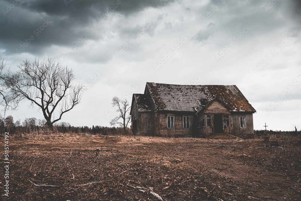 One old abandoned horror wooden house,dramatic stormy clouds with trees at autumn evening.Toned. One old abandoned horror wooden house,dramatic stormy clouds with trees at autumn evening.Toned.