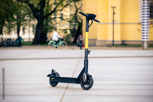 Electric scooter standing on the street with city buildings in the background. E-scooter, kick scooter using with mobile app. Modern, ecological, eco-friendly transport. Summer and spring transport photo