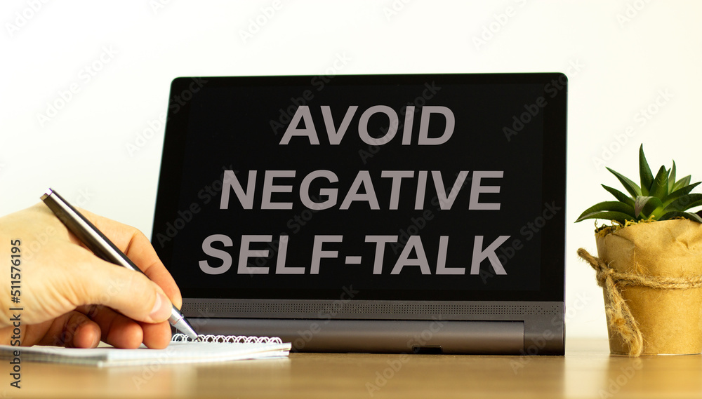 Avoid negative self-talk symbol. Concept words Avoid negative self-talk on the black tablet. Businessman hand with pen. Psychological and Avoid negative self-talk concept. Copy space. Avoid negative self-talk symbol. Concept words Avoid negative self-talk on the black tablet. Businessman hand with pen. Psychological and Avoid negative self-talk concept. Copy space.