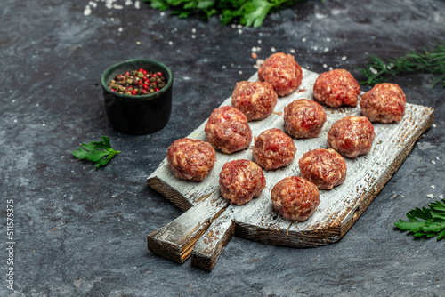 raw meatballs on wooden board, minced pork meat with spices on a dark background. Food recipe background. Close up