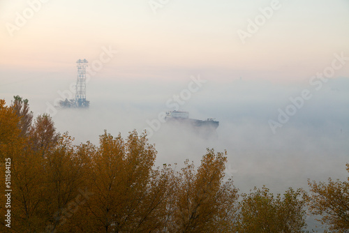 Foggy morning over river dnipro with a barge ship and wires at dawn. Ukraine, peace.