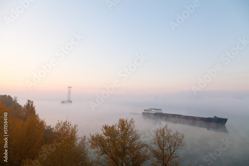 A barge ship on the river, foggy morning, pole and wires in the background. Ukraine, peace before war. © Uilia
