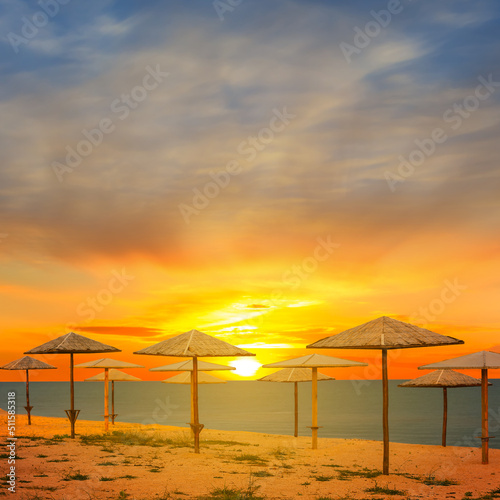 sandy sea beach with sun umbrella at the sunset © Yuriy Kulik