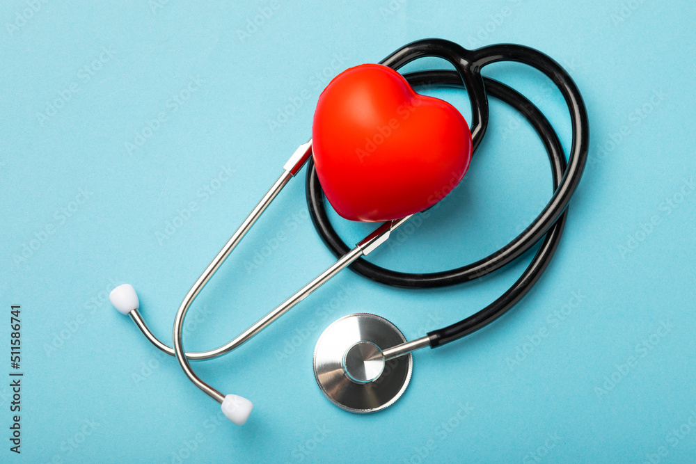 Black stethoscope and red heart on a blue background, close up.Health care. Place for text. Medicine concept. Cardiology concept. Black stethoscope and red heart on a blue background, close up.Health care. Place for text. Medicine concept. Cardiology concept.
