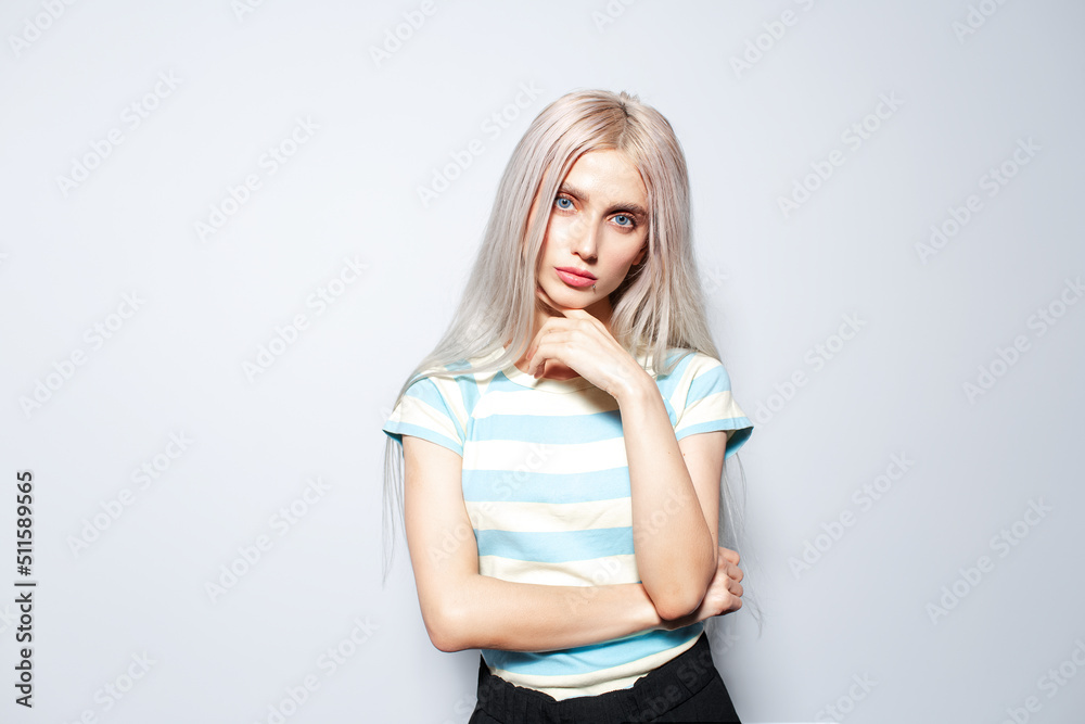 Portrait of fashionable blonde girl in striped shirt on white background.
