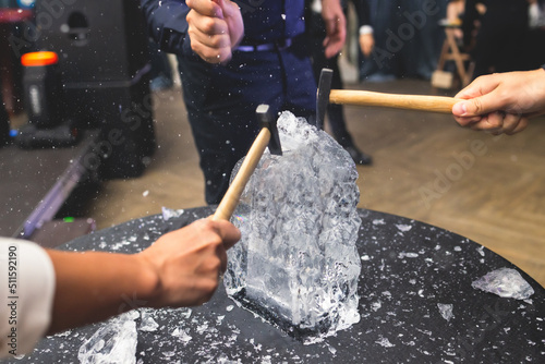 Process of breaking the ice with hammer and ice pick, group of people smashing shattered ice cube, team work success concept, concept of starting event, conversation photo