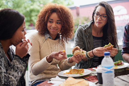 This is the best place in town. Cropped shot of a friends eating burgers outdoors.