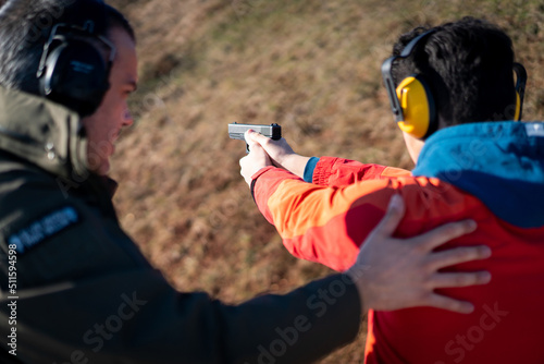 Trainer helping young person to aim with handgun at combat training. High quality photo
