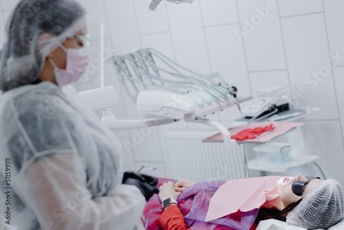 A female dentist in a dental office prepares a patient for treatment.